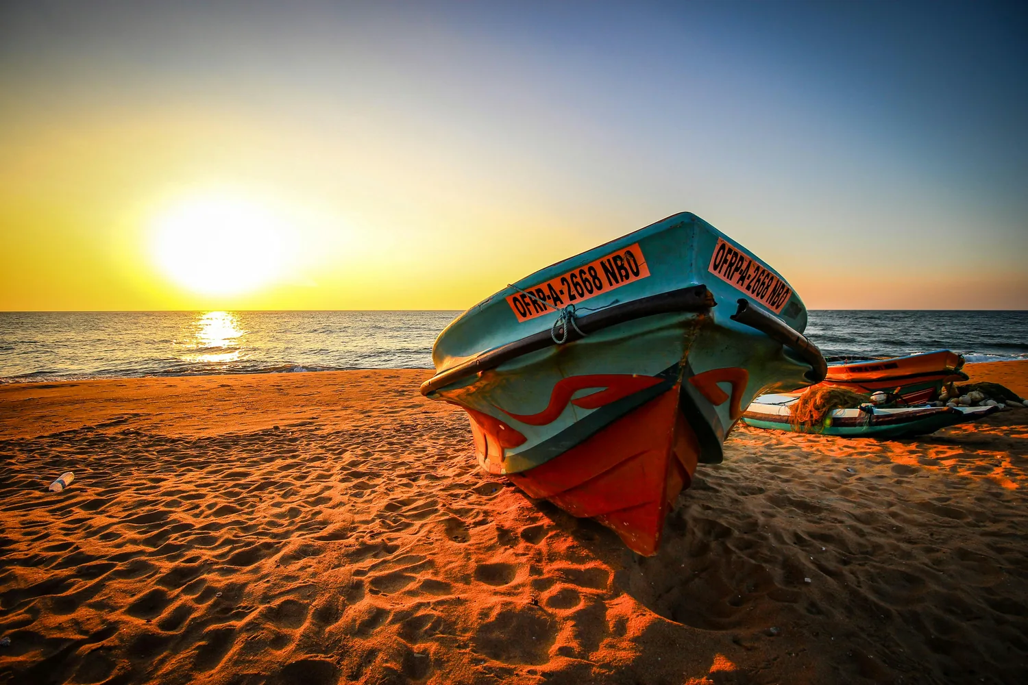 Fishing boat resting on the sand at sunset in Bentota